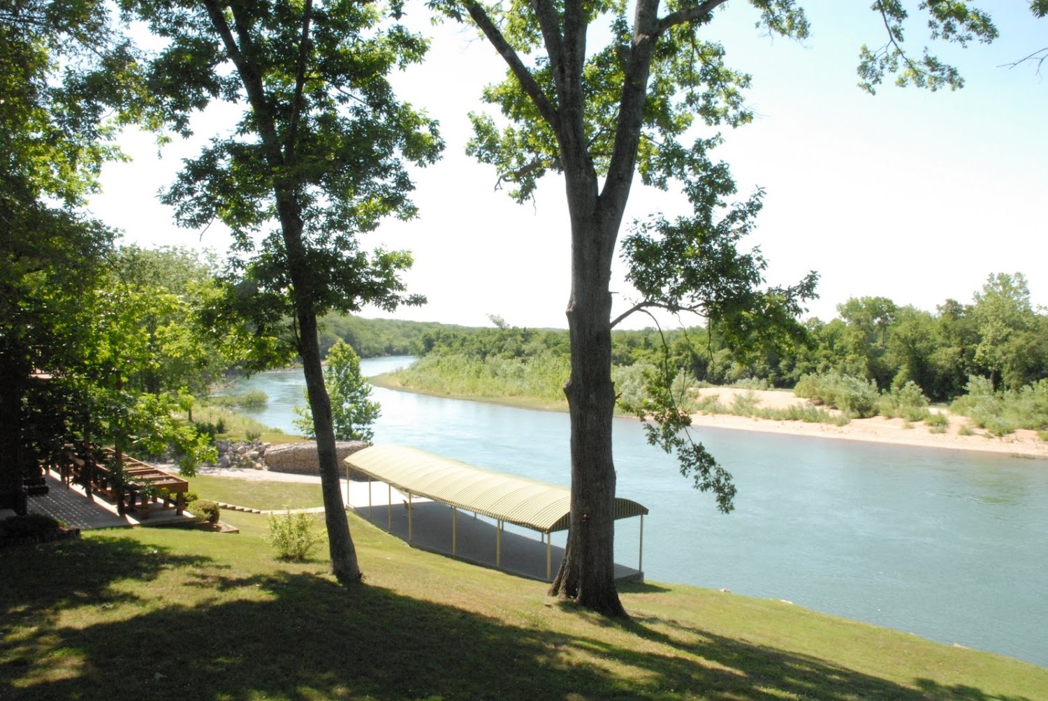 Current River view from 251 Walleye Lane with private boat-ramp canopy and riverside lawn